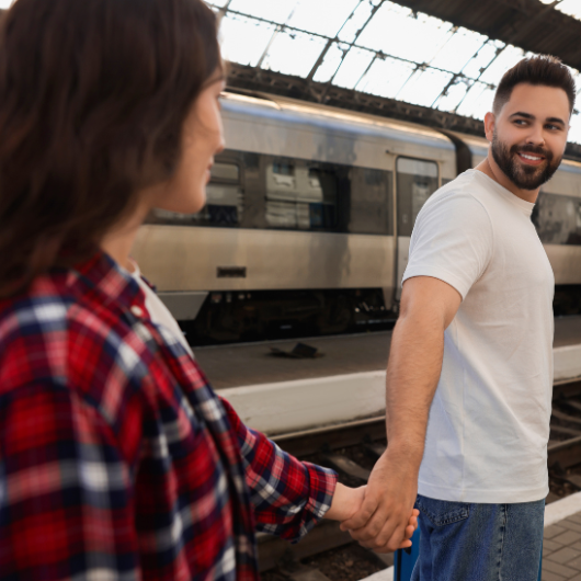 Couple se tenant la main sur un quai de gare, symbolisant la distance et les moyens de garder le lien avec des jeux à distance en couple.
