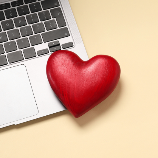 Cœur rouge posé sur un ordinateur portable, représentant l’amour connecté dans une relation à distance.